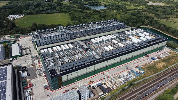 Aerial view of a data center near green fields, a lake, and railway tracks