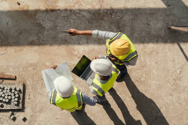 Engineers reviewing blueprints at a construction site, top view